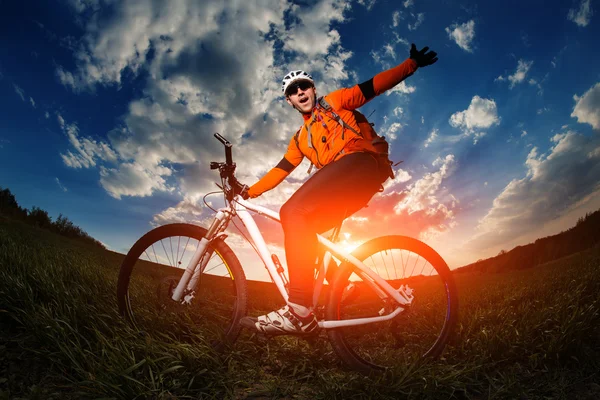 Motorista en jersey naranja montar en el campo de verano verde —  Fotos de Stock