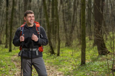 Erkek yürüyüşçü ormanda yürürken yan tarafa bakıyor.