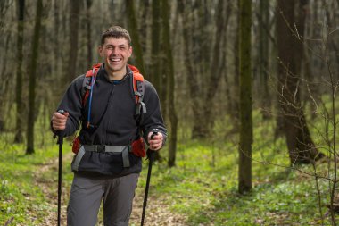 Erkek yürüyüşçü ormanda yürürken yan tarafa bakıyor.
