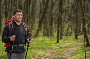 Erkek yürüyüşçü ormanda yürürken yan tarafa bakıyor.