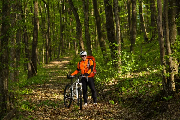 Ciclista montando a bicicleta em uma trilha na floresta de verão — Fotografia de Stock