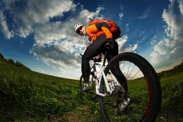 Motociclist în tricou portocaliu călărie pe câmp verde de vară — Fotografie, imagine de stoc