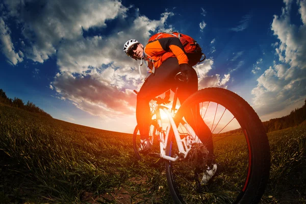 Motociclista in jersey arancione a cavallo sul campo estivo verde — Foto Stock