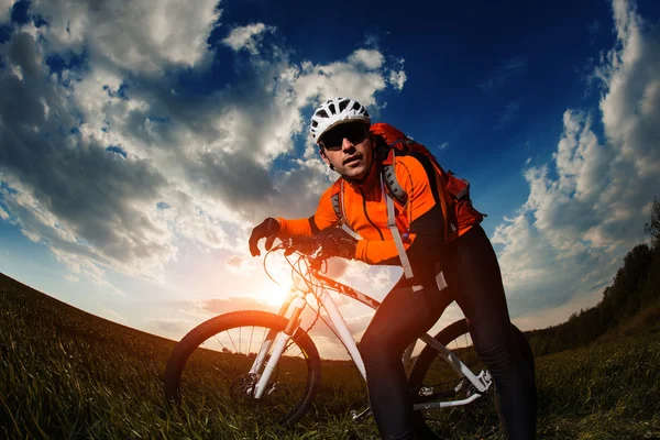Motorista en jersey naranja montar en el campo de verano verde —  Fotos de Stock