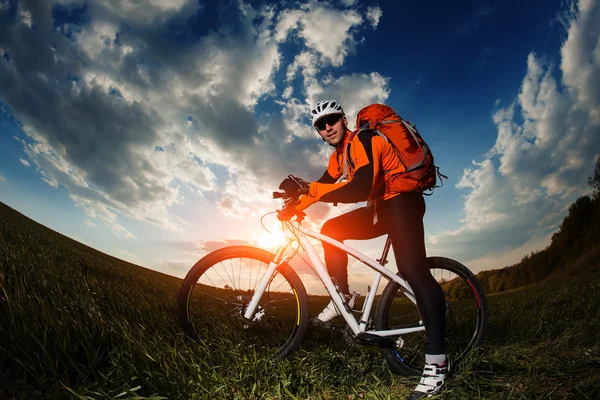 Motociclista in jersey arancione a cavallo sul campo estivo verde — Foto Stock