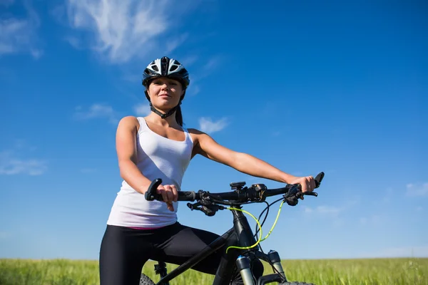 Весела красива молода жінка з велосипедом і шоломом на полі — стокове фото