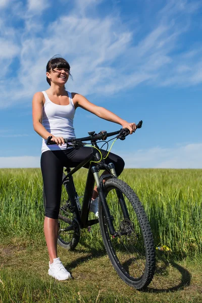 Жінка збирається кататися на велосипеді в сонячний день в сільській місцевості — стокове фото