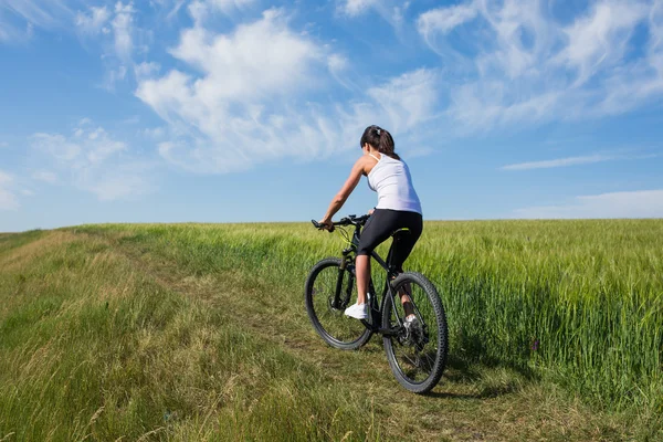 Vrouw gaat voor fietstocht op zonnige dag op platteland — Stockfoto