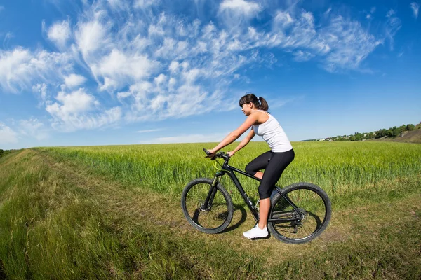 Γυναίκα πηγαίνει για βόλτα με ποδήλατο στην ηλιόλουστη μέρα στην εξοχή — Φωτογραφία Αρχείου
