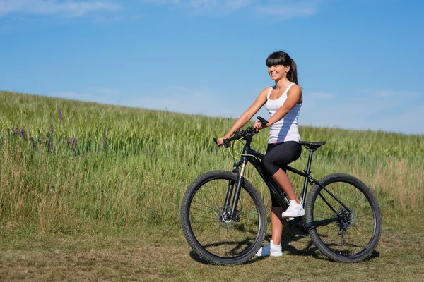 Ορεινή ποδηλασία ευτυχισμένος σπορ κορίτσι χαλαρώσετε στην ηλιόλουστη εξοχή λιβάδια — Φωτογραφία Αρχείου