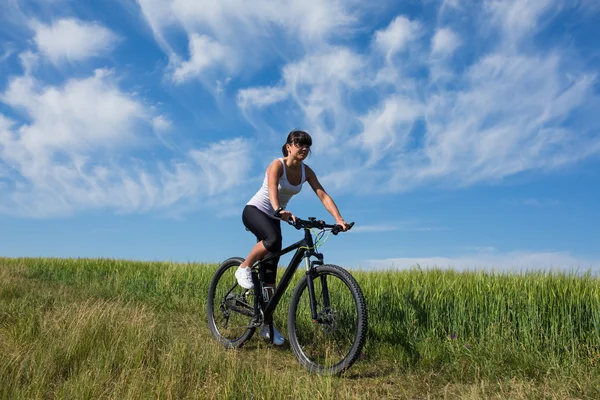 Mountainbiken gelukkig sportieve meisje ontspannen in zonnige landschap van weiden — Stockfoto