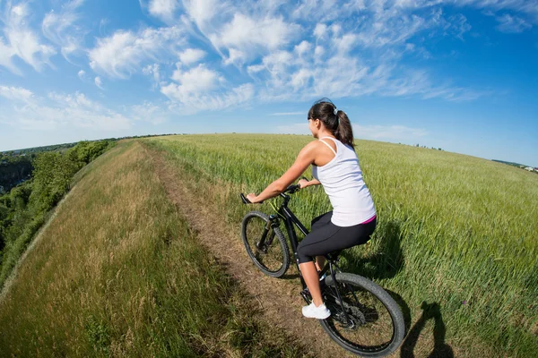 Mountainbiken gelukkig sportieve meisje ontspannen in zonnige landschap van weiden — Stockfoto