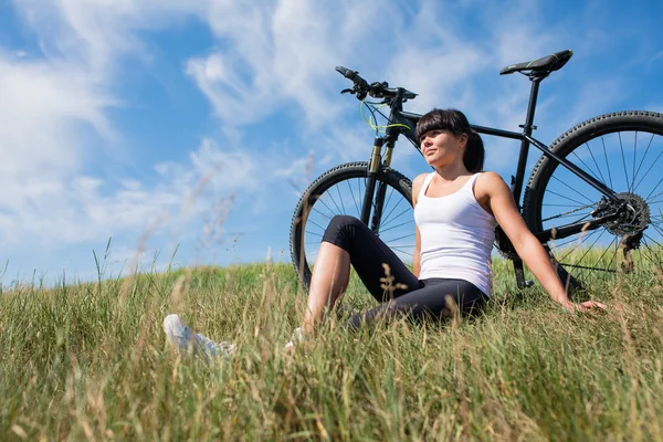 Mountainbiken gelukkig sportieve meisje ontspannen in zonnige landschap van weiden — Stockfoto