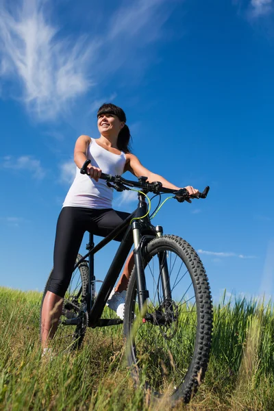 Sport fiets vrouw op de weide met een prachtig landschap — Stockfoto