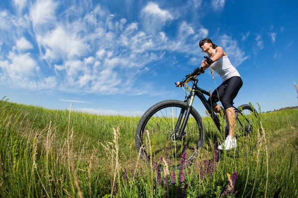 Deporte bicicleta mujer en el prado con un hermoso paisaje —  Fotos de Stock