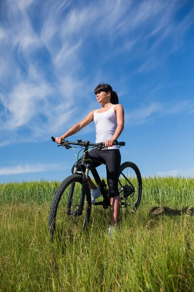 Sport fiets vrouw op de weide met een prachtig landschap — Stockfoto