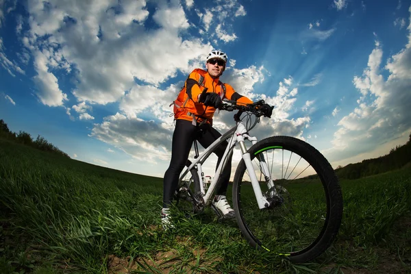 Młody człowiek, jazda na rowerze przez głębokie trawy z plecaka — Zdjęcie stockowe