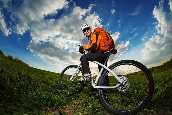 젊은 남자 배낭 깊은 잔디를 통해 자전거를 타고 — 스톡 사진