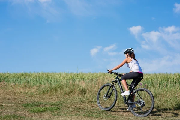 Велосипедистка на лугу с красивым пейзажем — стоковое фото