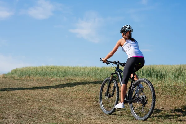 Девушка с велосипедом на весеннем лугу — стоковое фото