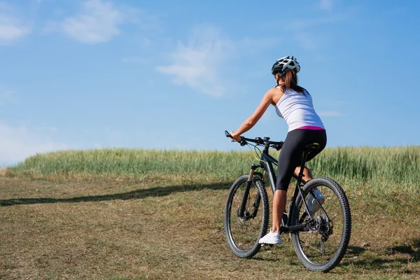 Giovane signora con bicicletta su un prato primaverile — Foto Stock