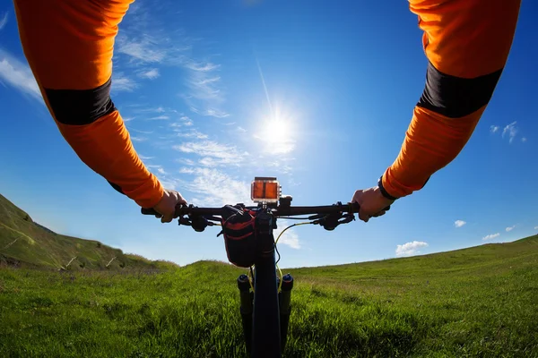 Manos en chaqueta naranja sosteniendo el manillar de una bicicleta —  Fotos de Stock