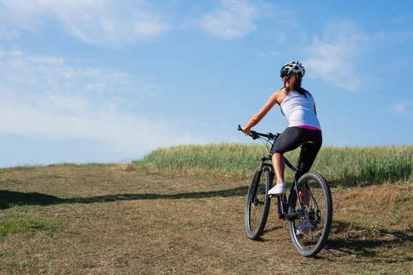 Jonge dame met fiets op een lente-weide — Stockfoto