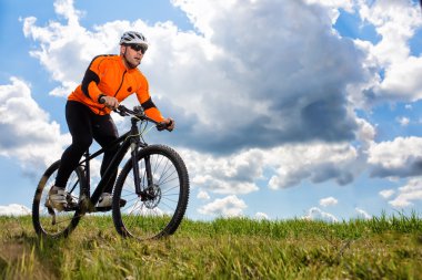 Genç adam yeşil çayır kırsal bir yolda Bisiklete binme