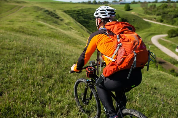 Ung man cykla på en lantlig väg genom gröna ängen — Stockfoto