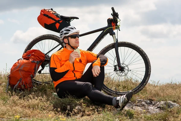 Actieve man op fiets zit en eten boterham — Stockfoto