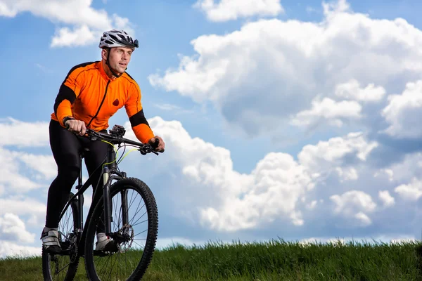 Egy vidéki úton keresztül zöld rét kerékpáros fiatalember — Stock Fotó