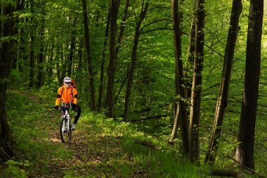Orman yolu üzerinde turuncu mayoyu motorcu