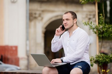 dizüstü bilgisayar ve telefon taş bankta genç adam