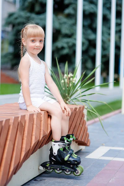 Malá holka jezdí na kolečkových bruslích v parku — Stock fotografie