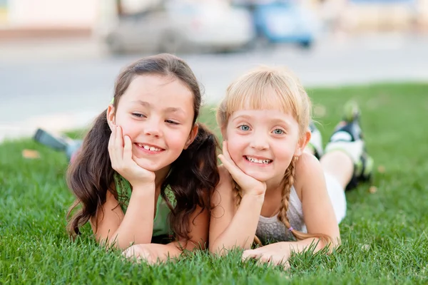 Duas meninas em patins deitado na grama — Fotografia de Stock