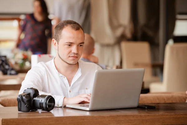 photographer with the camera works on his laptop