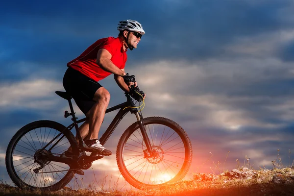 日の出背景で丘の上に山自転車に乗る — ストック写真