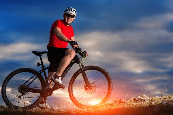 日の出背景で丘の上に山自転車に乗る — ストック写真