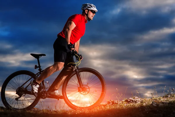 日の出背景で丘の上に山自転車に乗る — ストック写真