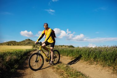 Genç adam kırsal bir yolda Bisiklete binme