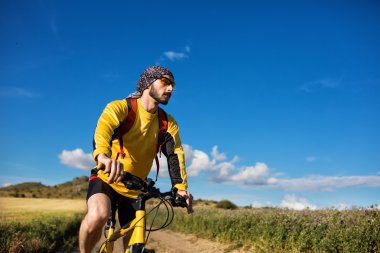 Genç adam kırsal bir yolda Bisiklete binme