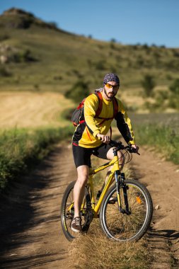 Genç adam kırsal bir yolda Bisiklete binme