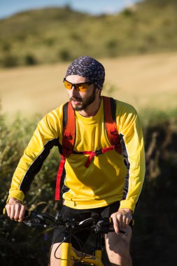 Genç adam kırsal bir yolda Bisiklete binme