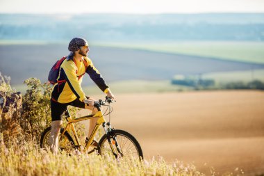 Genç adam kırsal bir yolda Bisiklete binme