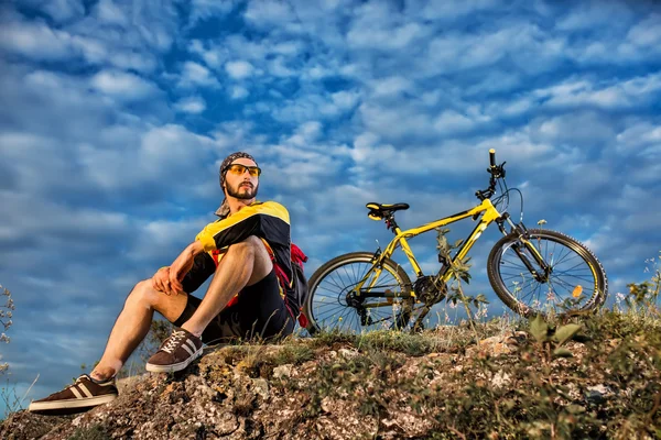 Rowerzysta, odpoczynek na świeżym powietrzu siedząc na trawie — Zdjęcie stockowe