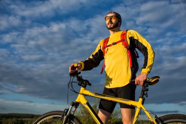 Bisikletçi yolda bisiklete biniyor.