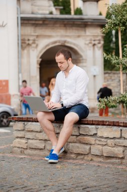 Parkta bir bankta taşınabilir bilgisayar kullanan adam