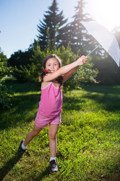 Happy girl dancing with umbrella in summer sun