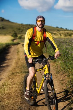 Genç adam kırsal bir yolda Bisiklete binme