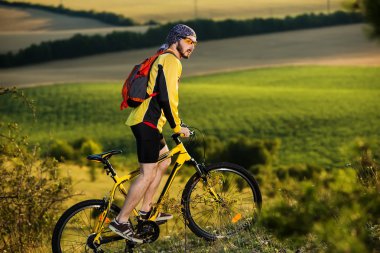 Genç adam kırsal bir yolda Bisiklete binme
